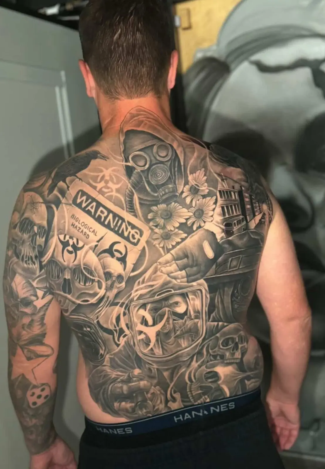 Detailed black-and-gray back tattoo with skull and warning motifs