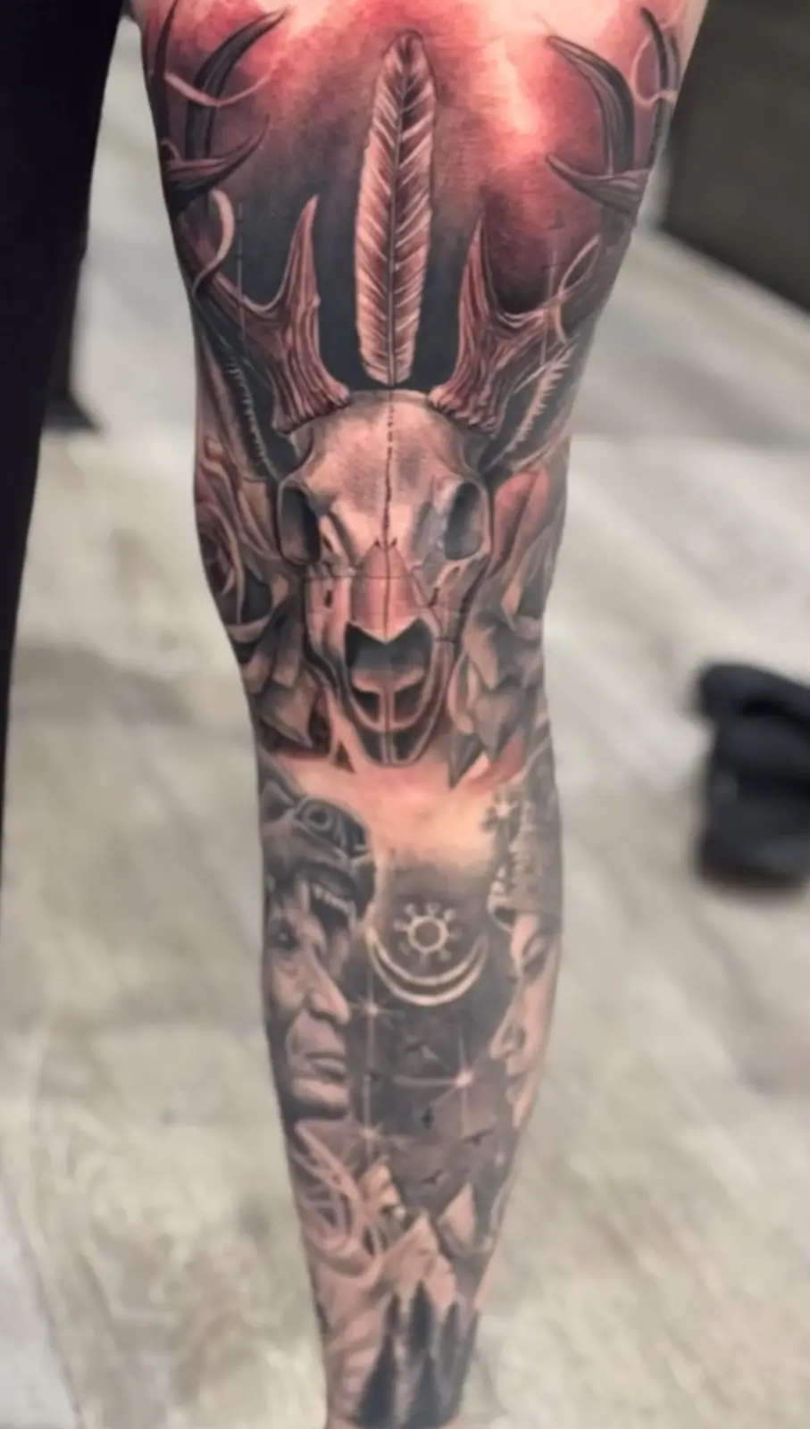 Black-and-gray skull and statue leg sleeve tattoo