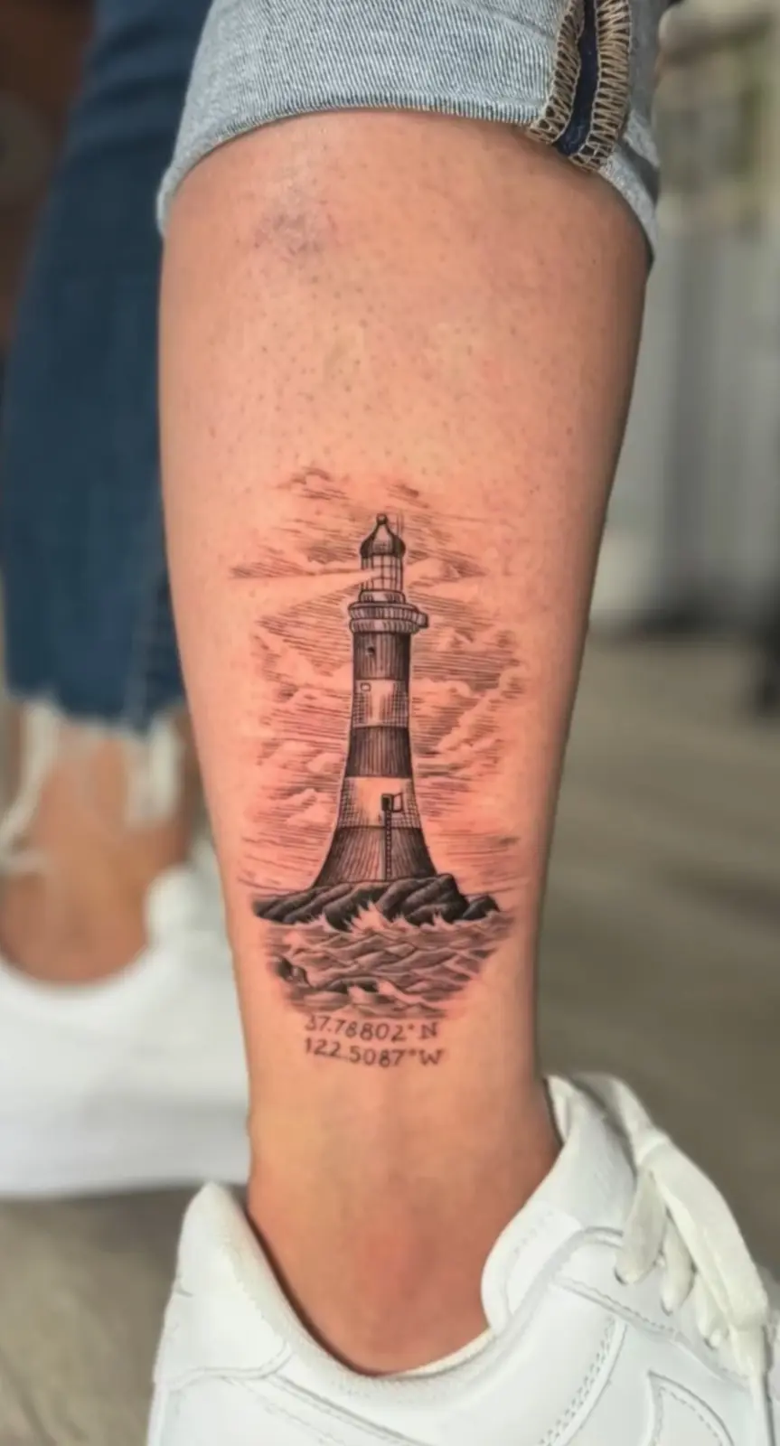 Fine-line lighthouse tattoo on a lower leg